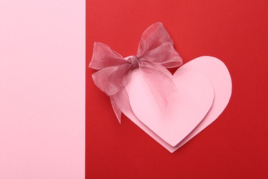 Pink decorative hearts with bow on color background, top view