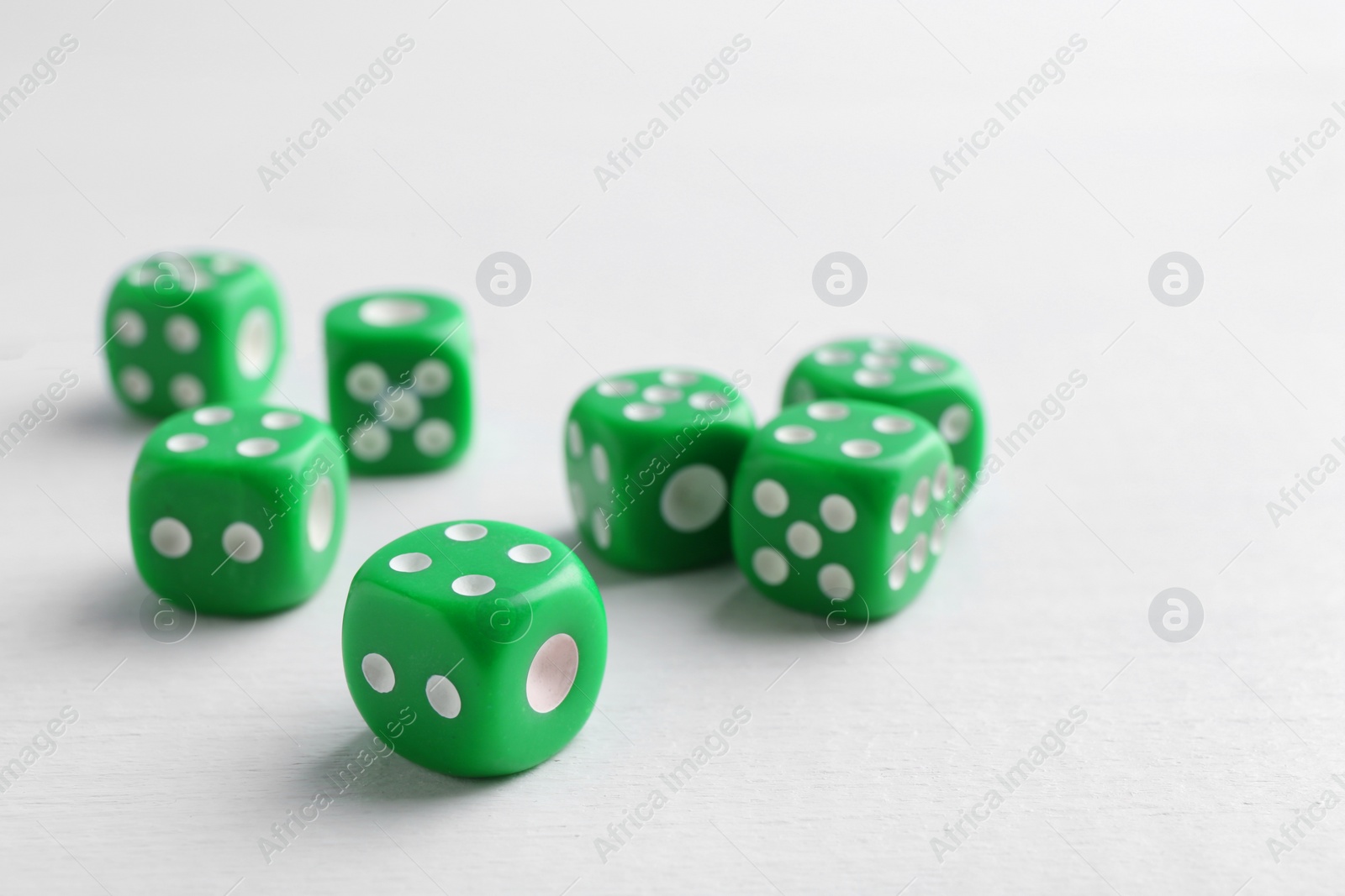 Photo of Many green game dices on white wooden table. Space for text