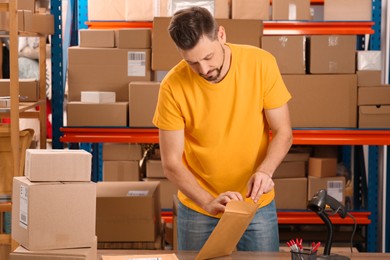 Photo of Post office worker with adhesive paper bag at counter indoors