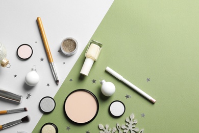Flat lay composition with makeup products and Christmas decor on color background. Space for text