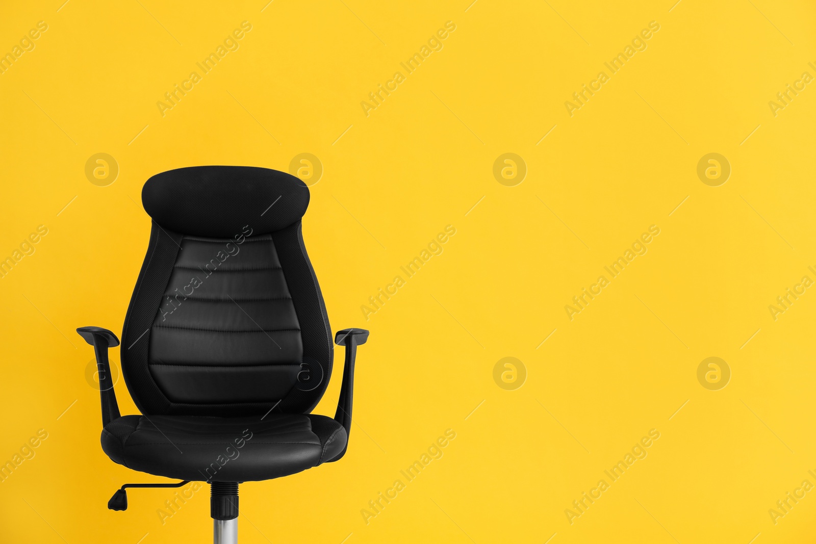 Photo of Modern office chair on yellow background. Space for text