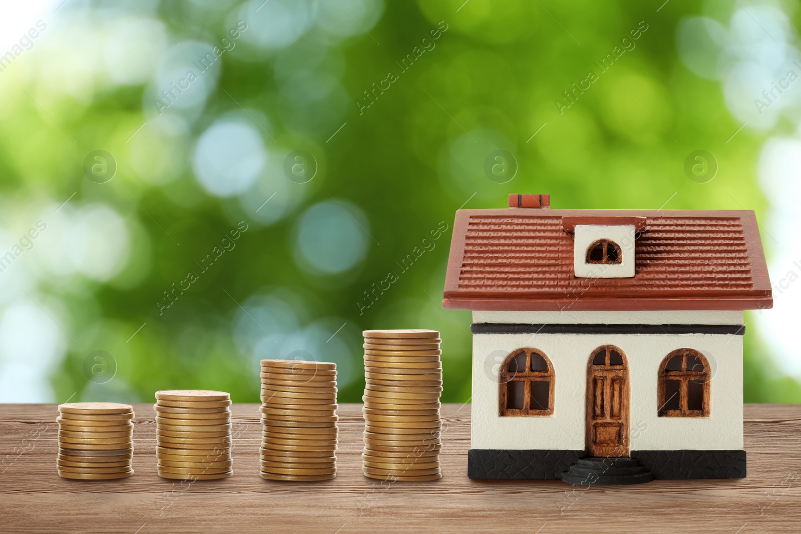 Image of Real estate investing. House model and coins on wooden table