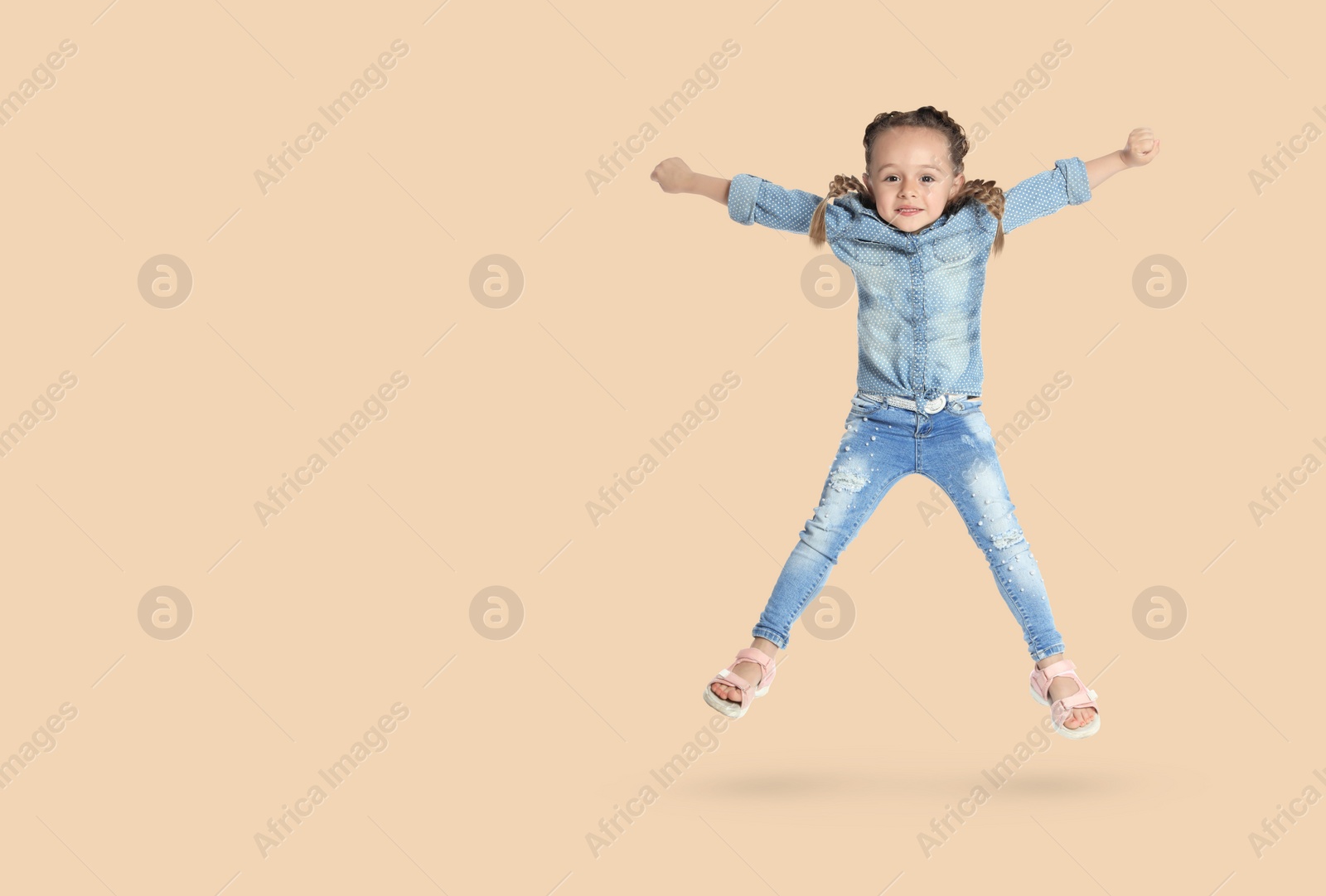 Image of Cute girl jumping on beige background, space for text