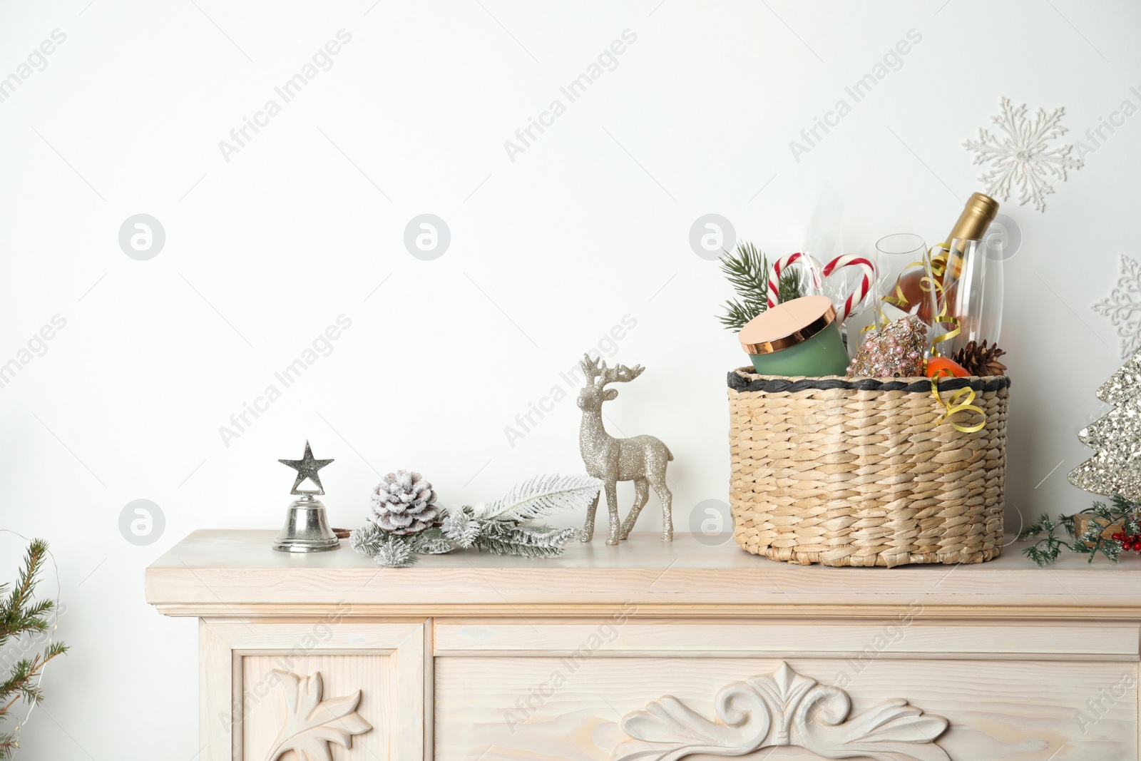 Photo of Wicker basket with gift set and Christmas decor on shelf. Space for text