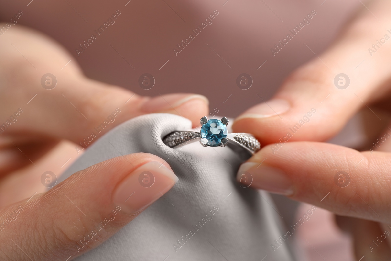 Photo of Jeweler cleaning topaz ring with microfiber cloth, closeup