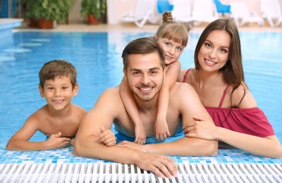 Photo of Happy family resting in swimming pool with refreshing water