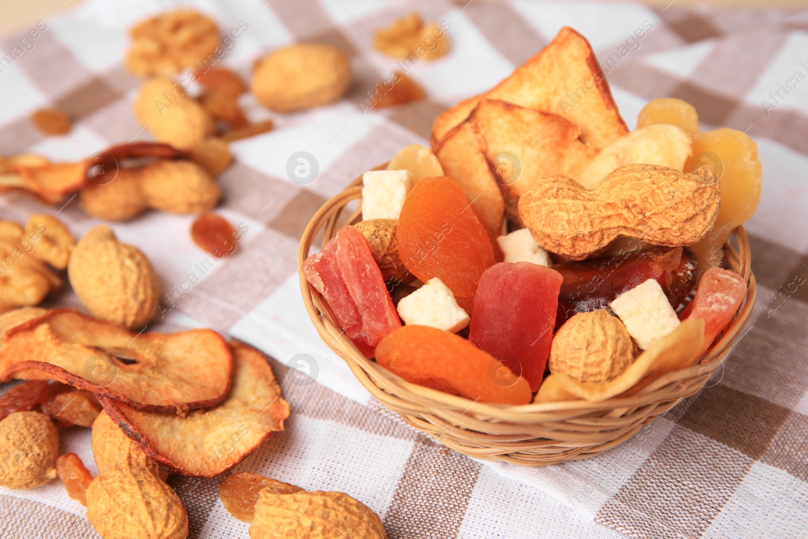 Photo of Mixed dried fruits and nuts on checkered tablecloth, closeup. Space for text