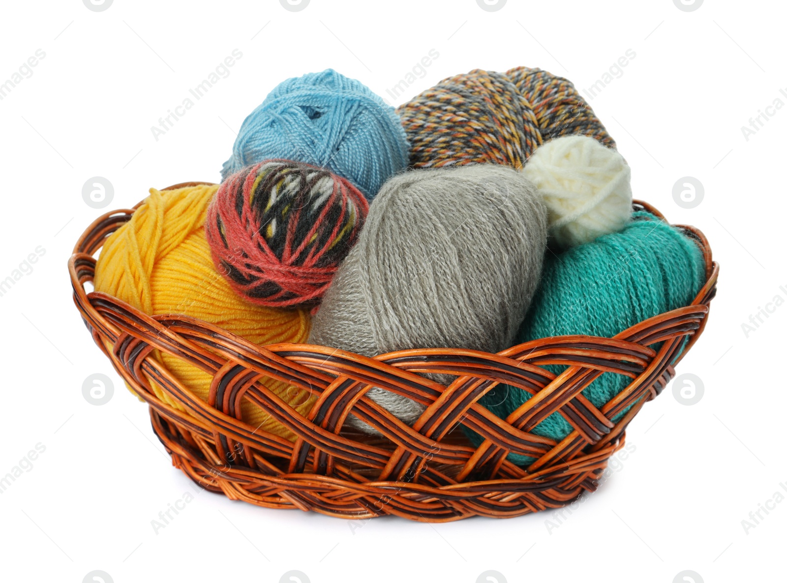 Photo of Different balls of woolen knitting yarns in wicker basket on white background