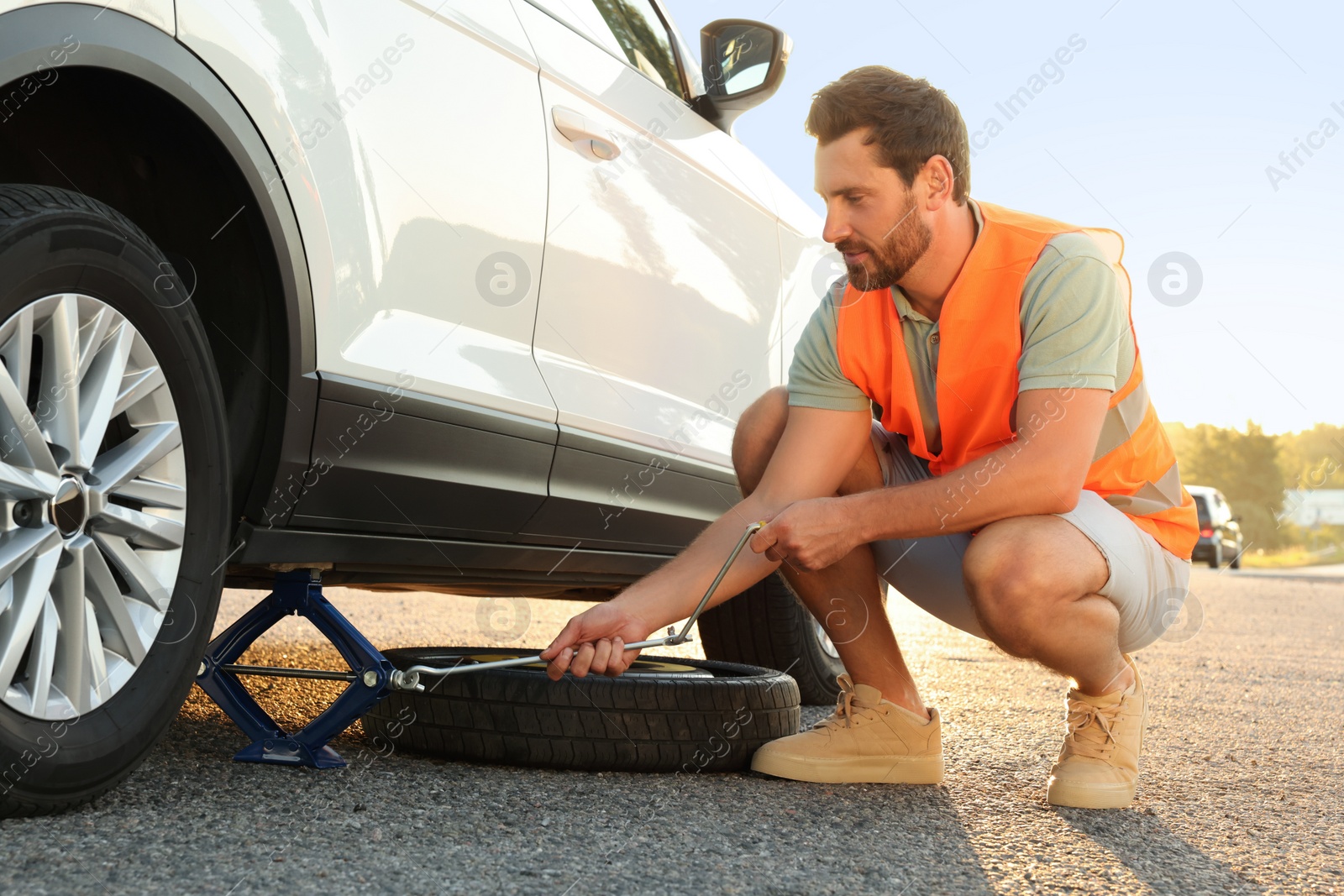 Photo of Man changing wheel of car on roadside