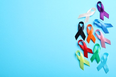 Photo of Colorful ribbons on light blue background, flat lay with space for text. World Cancer Day