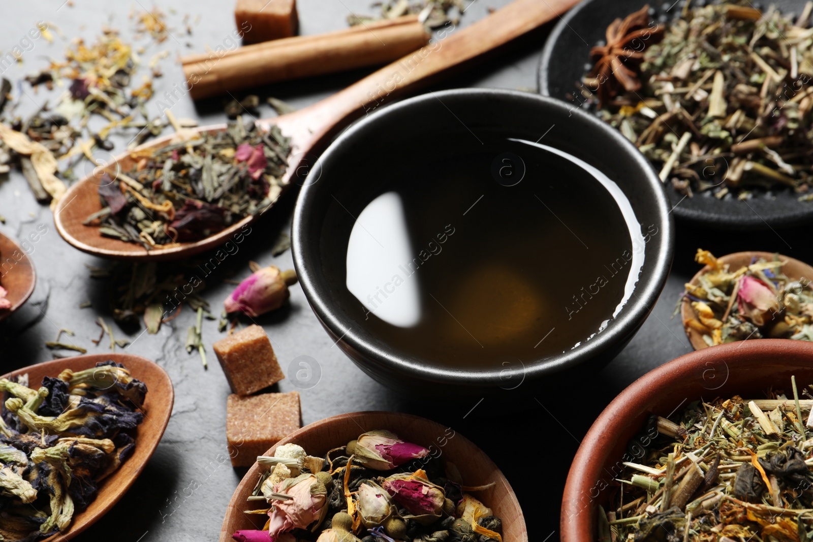 Photo of Fresh brewed tea and dry leaves on grey table, closeup