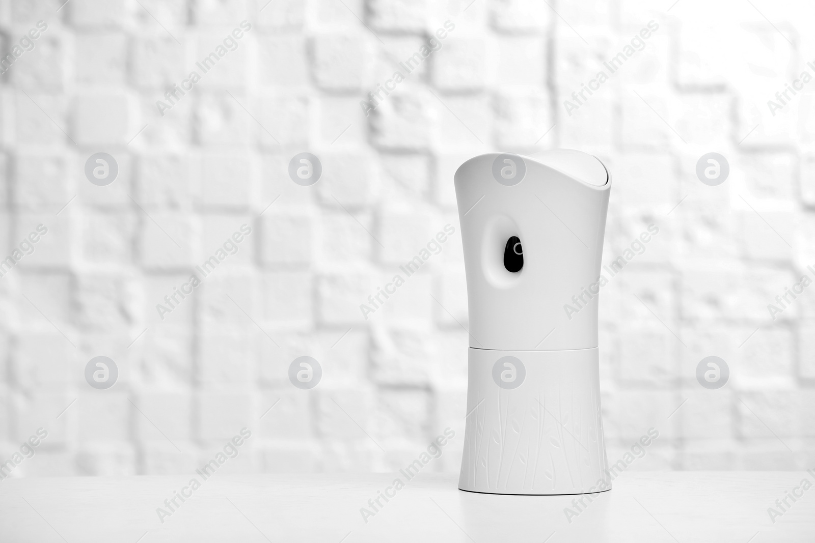 Photo of Automatic air freshener on table against light background