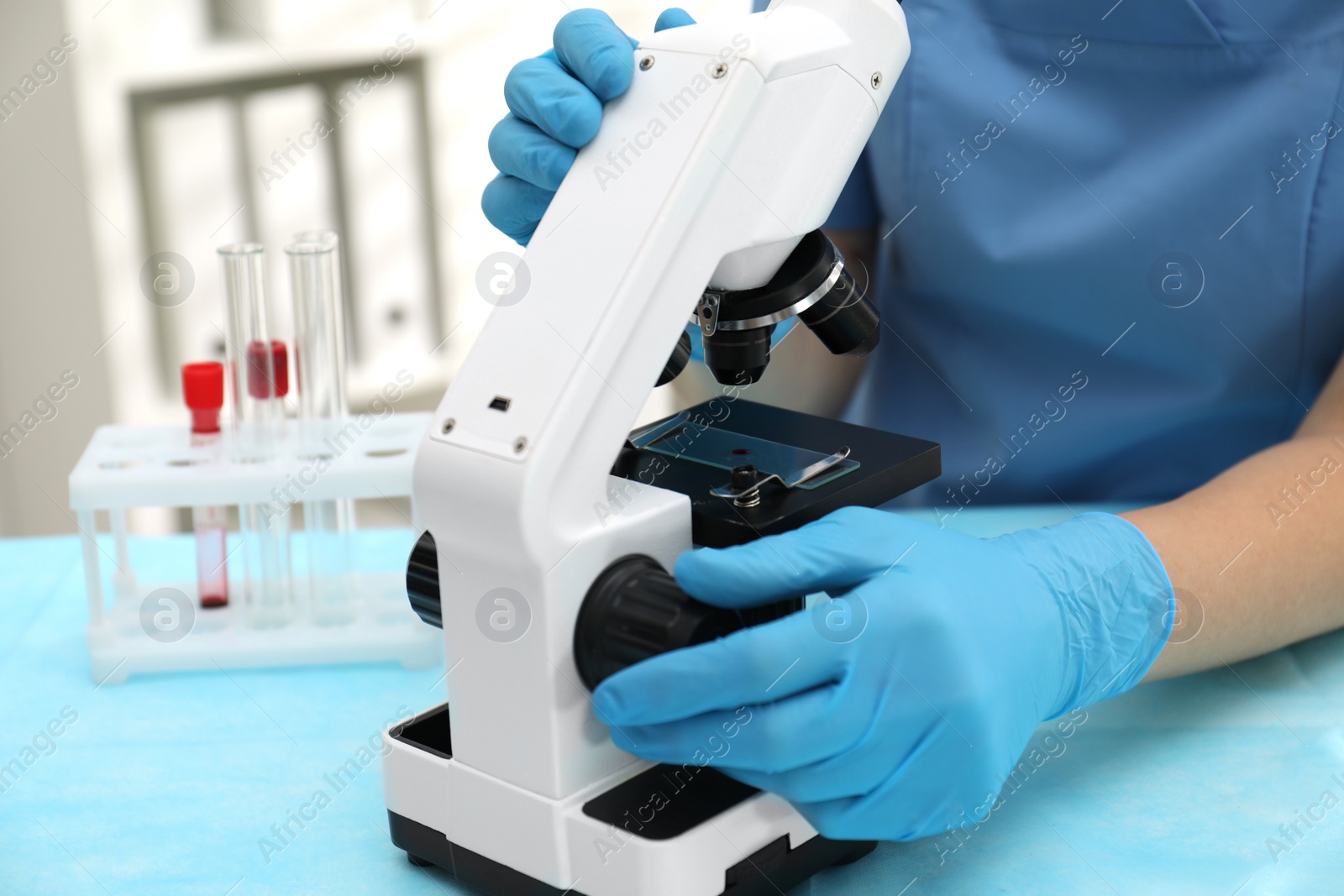 Photo of Doctor with blood sample from finger at table in laboratory, closeup