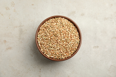 Photo of Uncooked green buckwheat grains in bowl on table, top view