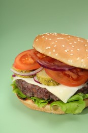 Photo of Burger with delicious patty on green background, closeup