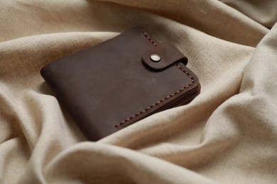 Stylish presentation of leather wallet on beige fabric, closeup