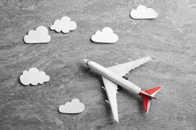 Photo of Toy airplane and clouds on grey stone background, flat lay