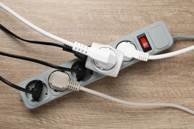 Power strip with extension cord on wooden floor, top view. Electrician's equipment