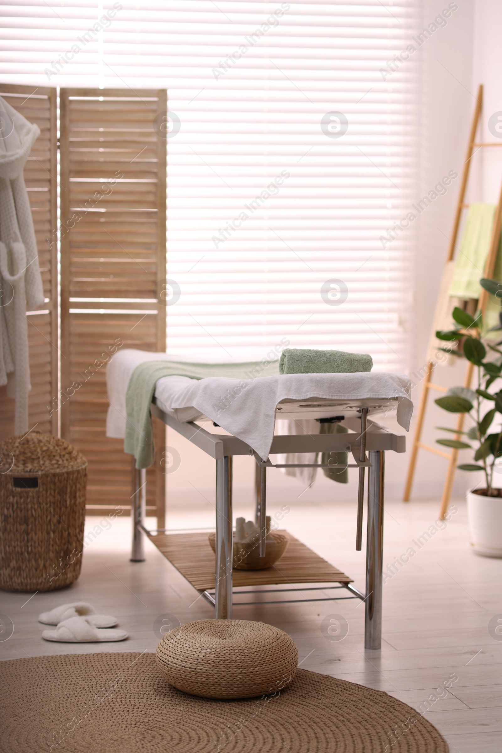 Photo of Comfortable massage table with clean towels in spa center