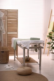 Photo of Comfortable massage table with clean towels in spa center