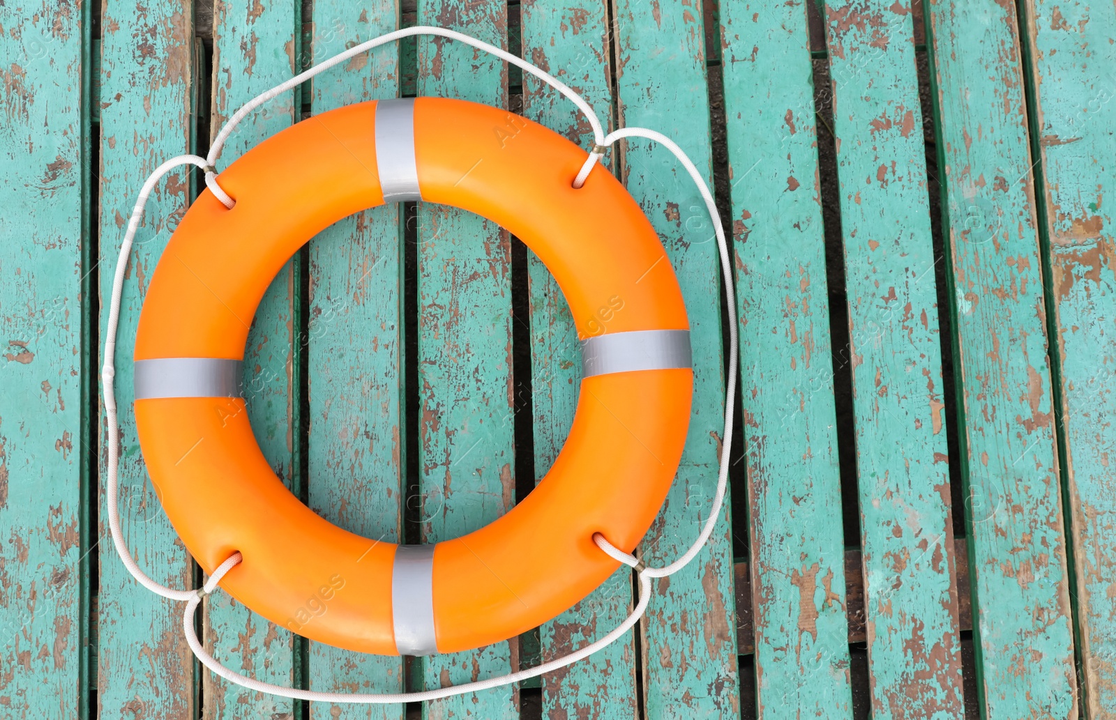 Photo of Orange life buoy on turquoise wooden background, top view. Space for text