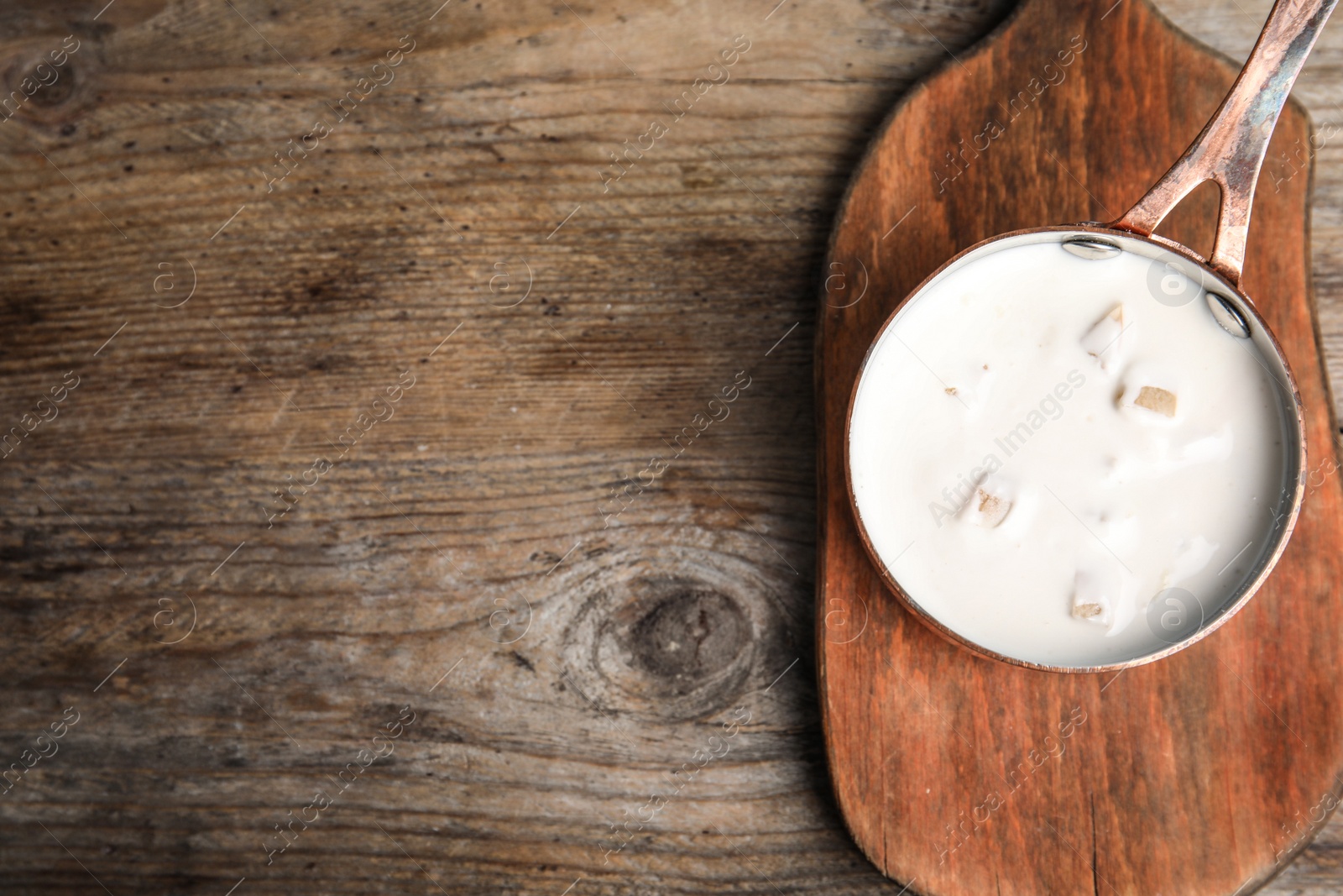 Photo of Delicious creamy sauce in pan on wooden table, top view. Space for text