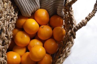 Photo of Net bag with many fresh ripe tangerines on white cloth, above view