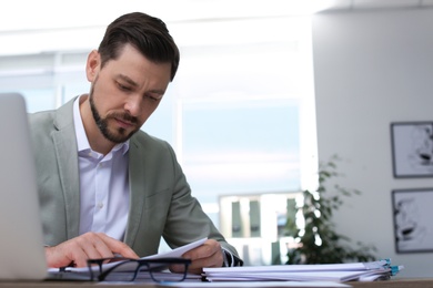 Photo of Businessman working with documents at table in office. Space for text
