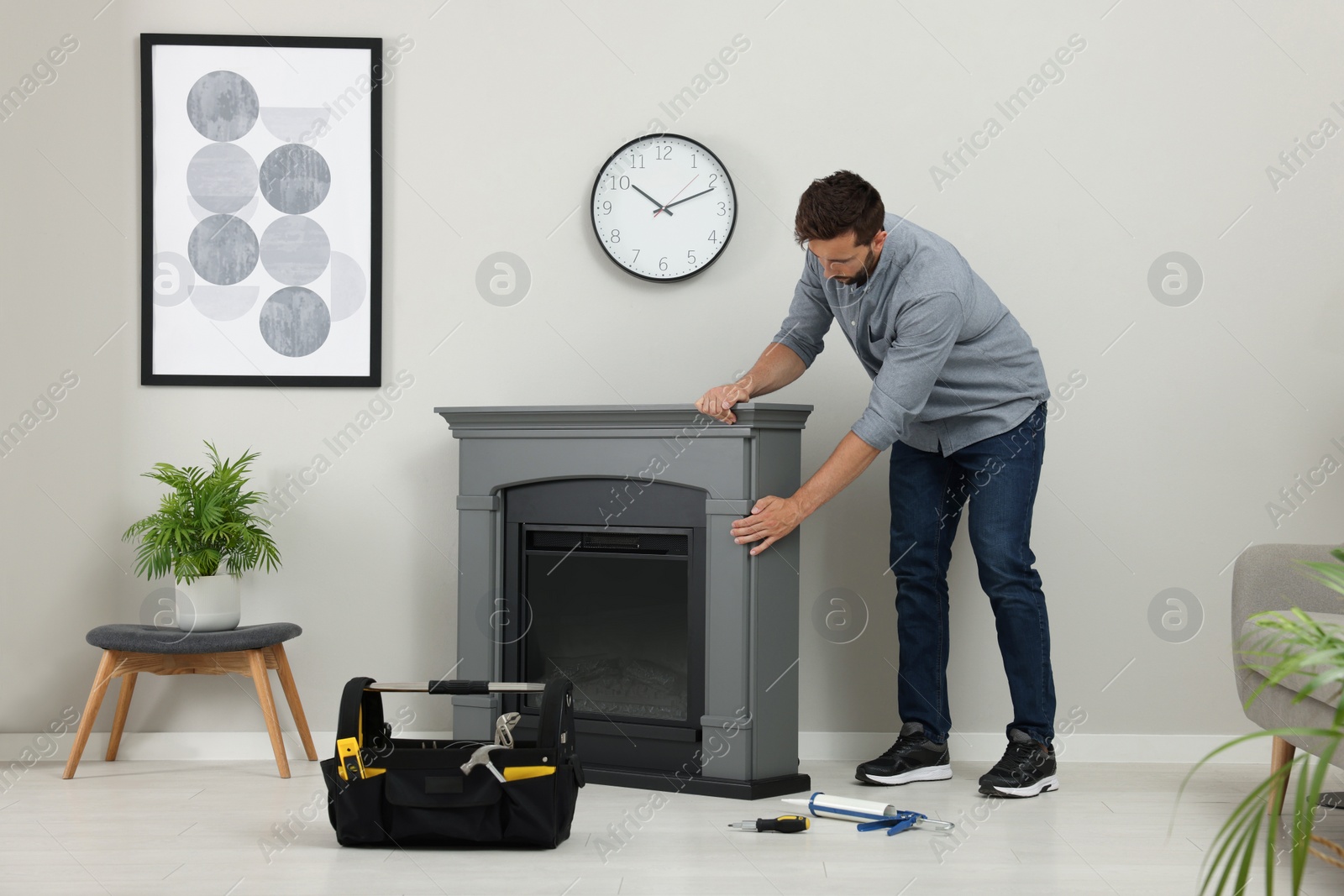 Photo of Man installing electric fireplace near wall in room