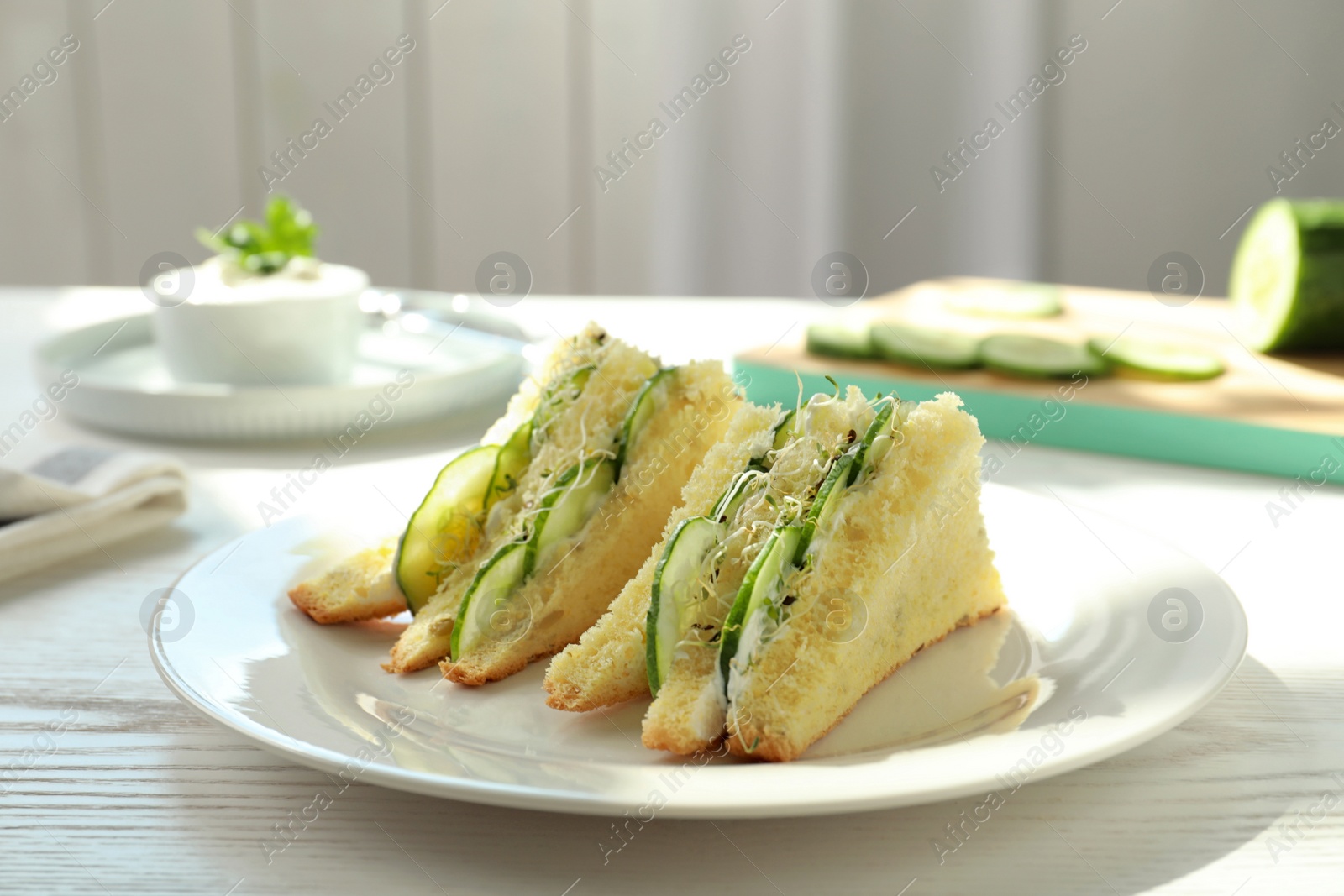 Photo of Plate with traditional English cucumber sandwiches on table