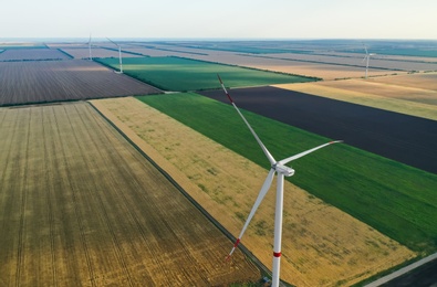 Photo of Modern windmill in field, space for text. Energy efficiency