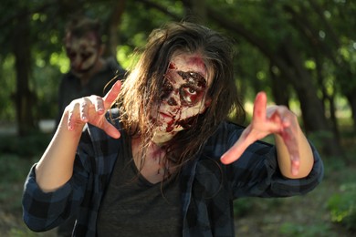 Scary zombies with bloody faces outdoors. Halloween monster