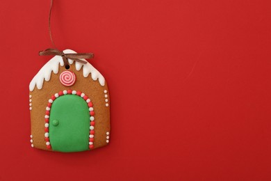 Photo of House shaped Christmas cookie on red background, top view. Space for text