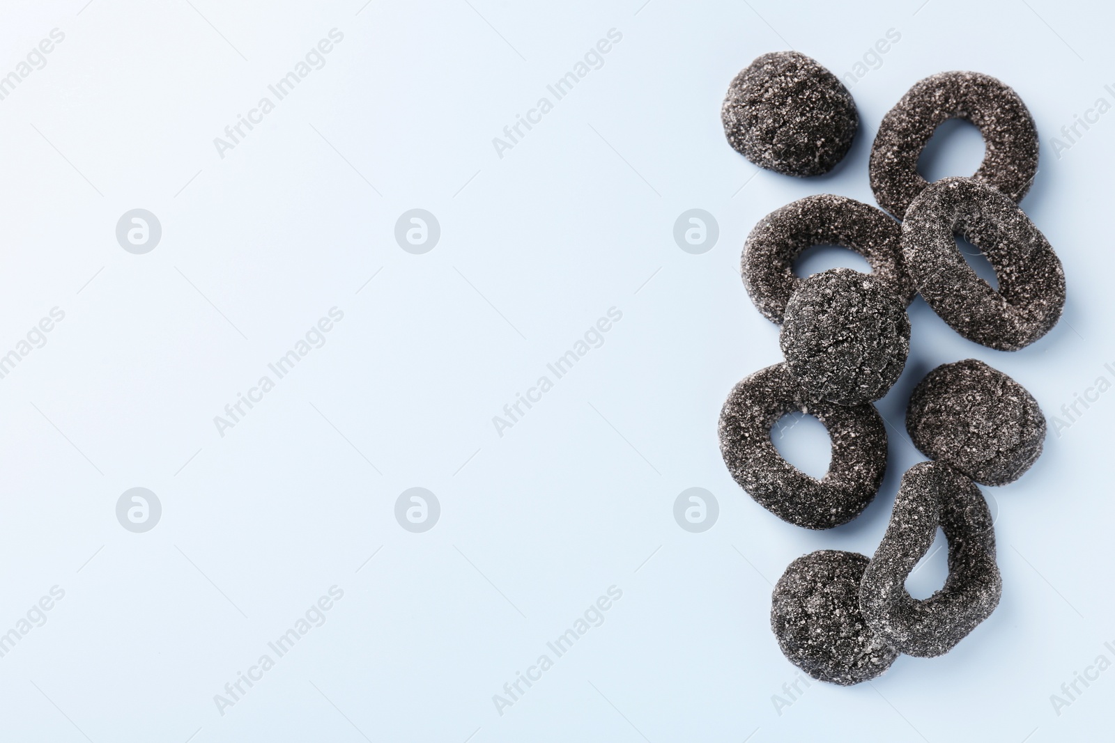 Photo of Tasty liquorice candies on light blue background, top view. Space for text