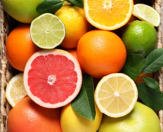 Photo of Different cut and whole citrus fruits on wooden table, top view