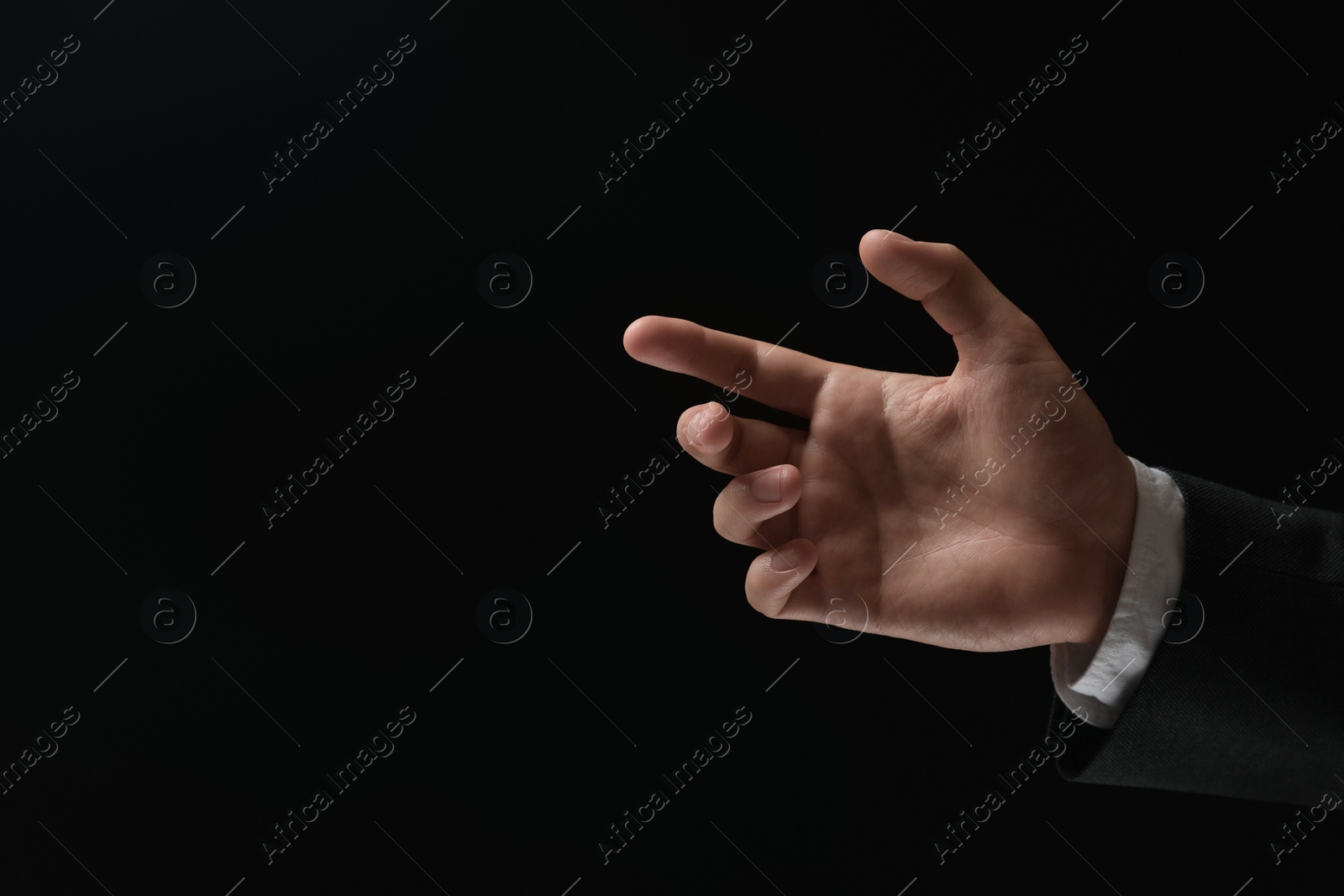 Photo of Man holding something in hand on black background, closeup. Space for text