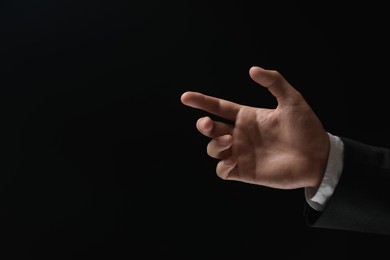 Photo of Man holding something in hand on black background, closeup. Space for text