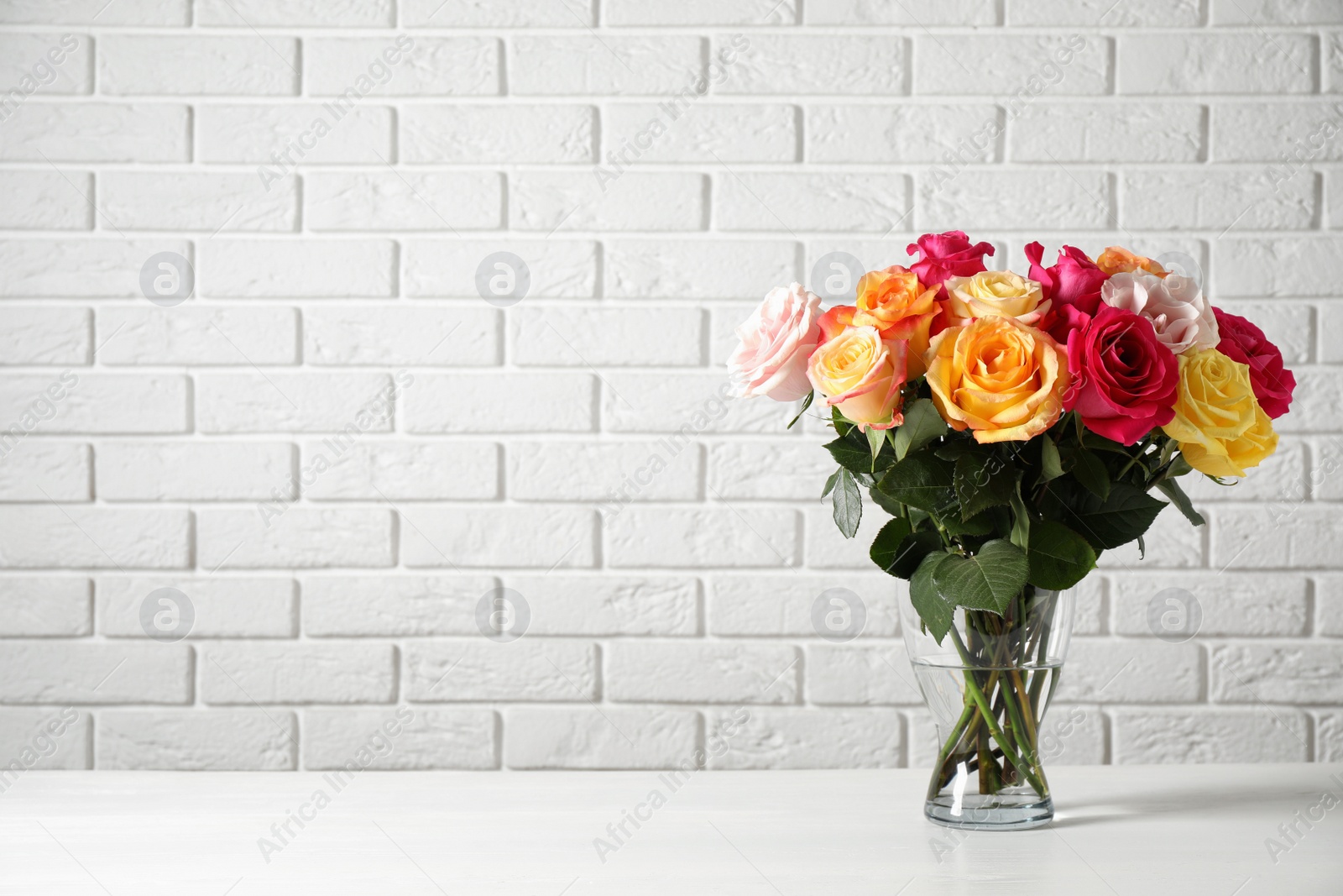 Photo of Luxury bouquet of fresh roses on white table. Space for text