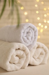 Photo of Rolled terry towels on white table near brick wall indoors, closeup