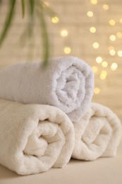 Rolled terry towels on white table near brick wall indoors, closeup