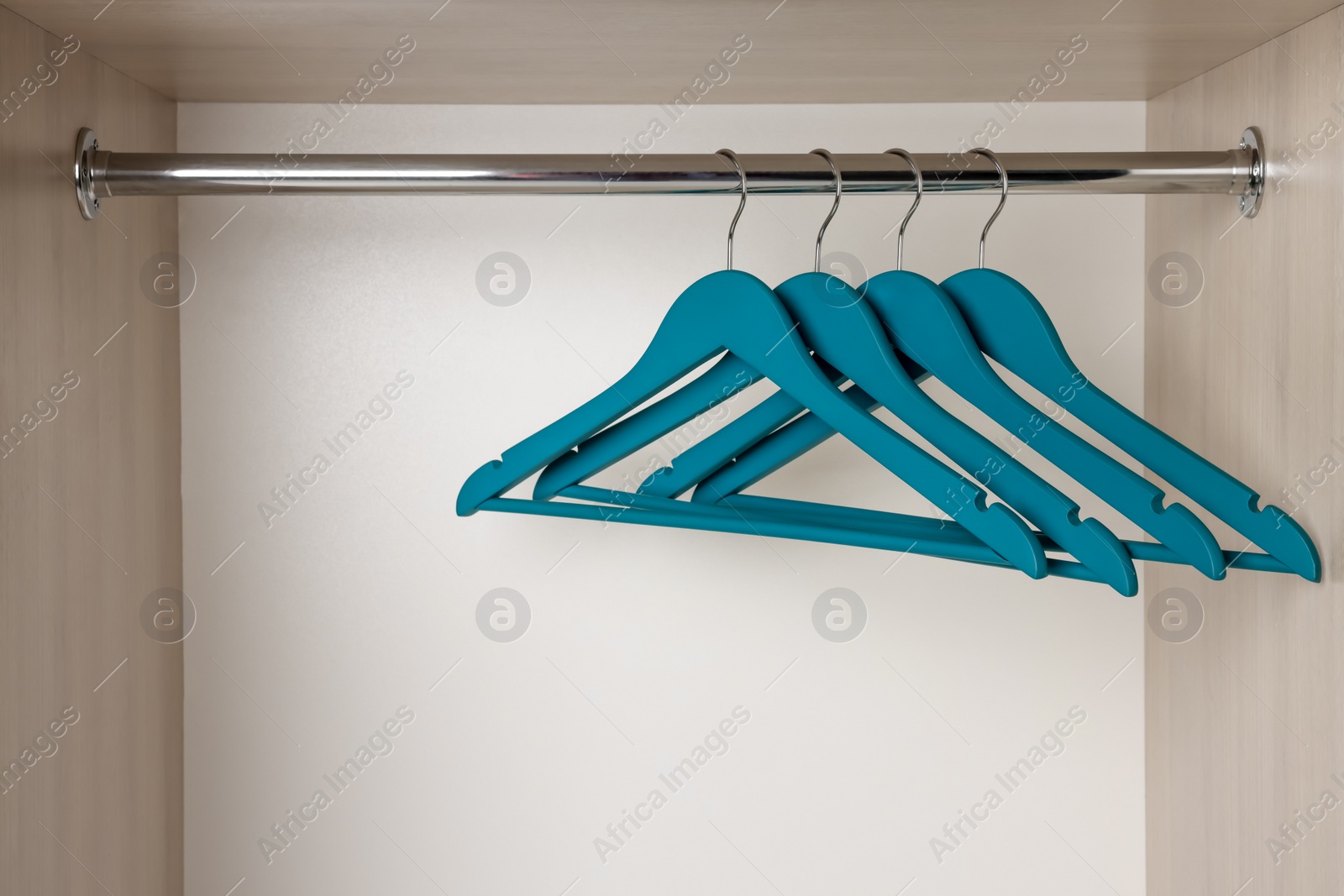 Photo of Set of blue clothes hangers on wardrobe rail