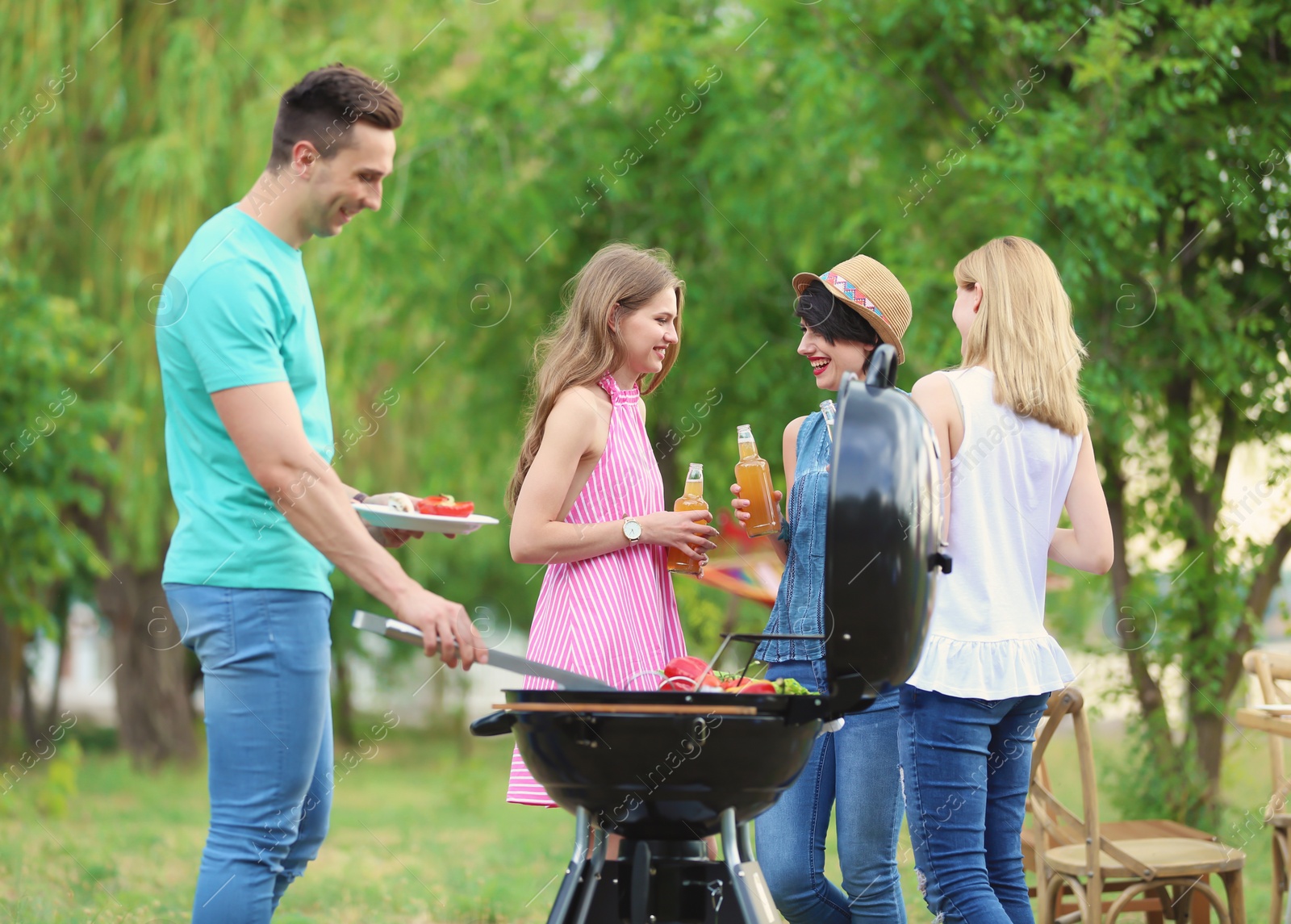 Photo of Young people having barbecue with modern grill outdoors