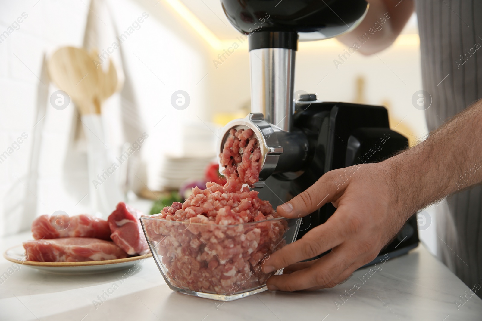 Photo of Man using modern meat grinder in kitchen, closeup