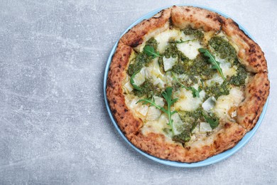 Photo of Delicious pizza with pesto, cheese and arugula on grey table, top view. Space for text