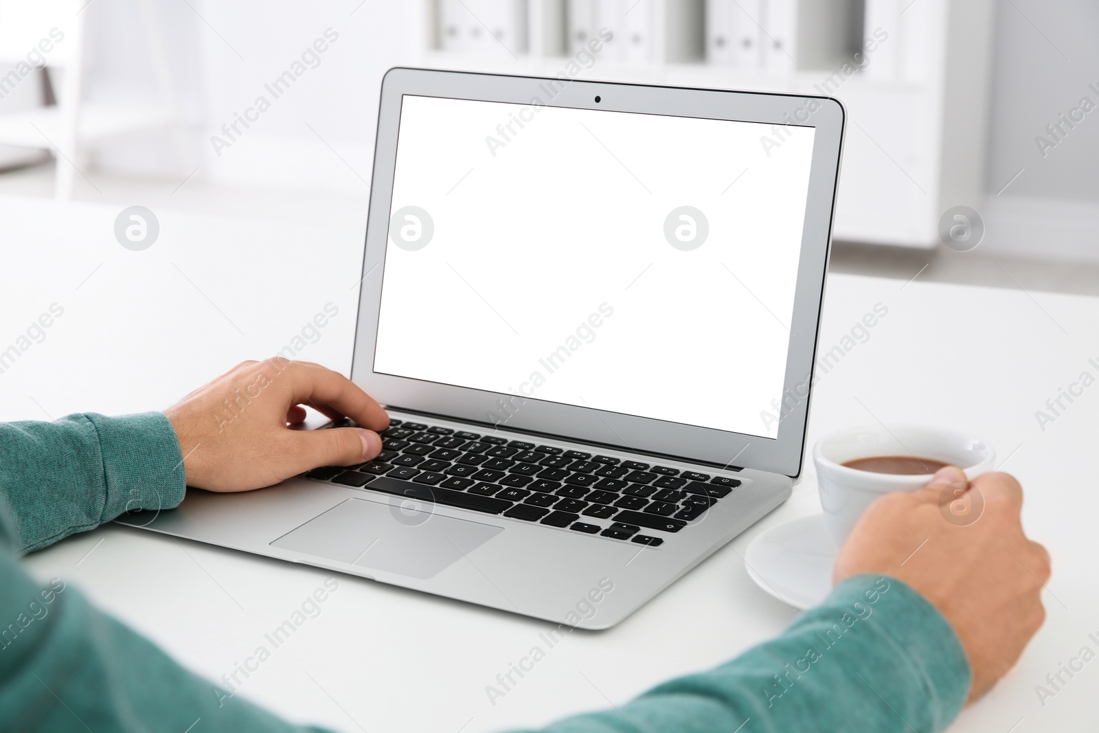 Photo of Young man working with modern laptop at table, closeup. Mockup for design