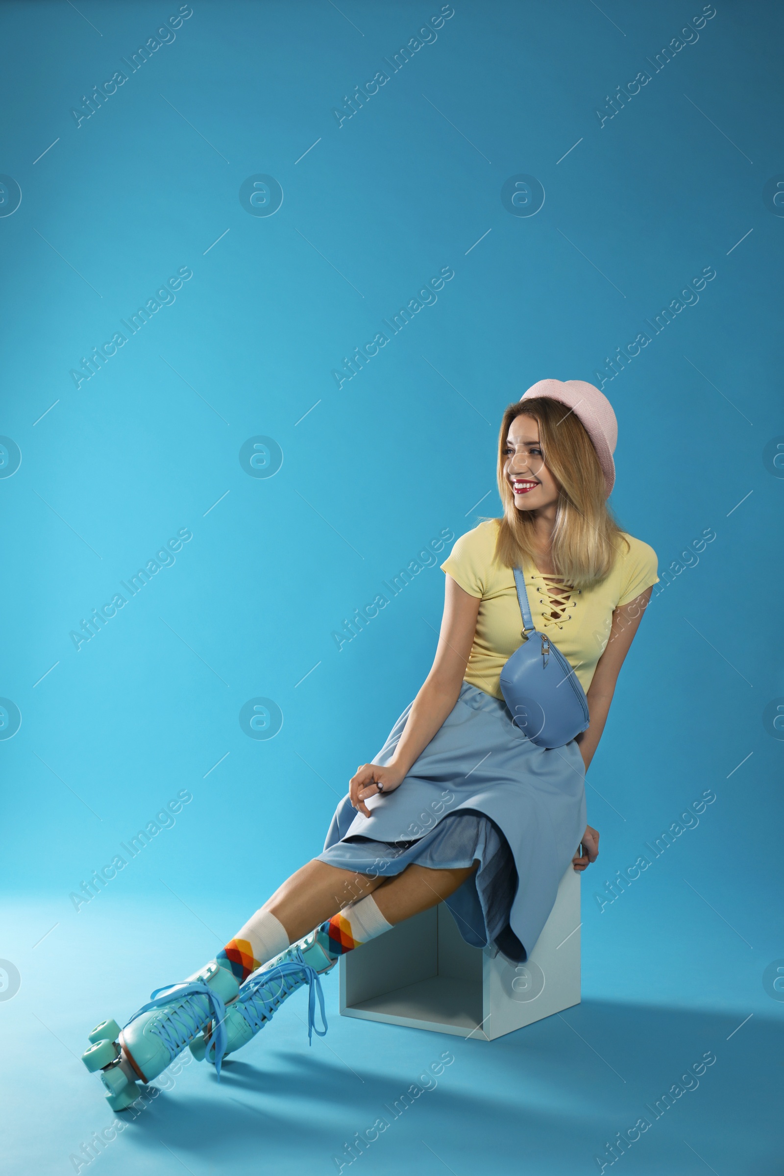 Photo of Young woman with retro roller skates on color background