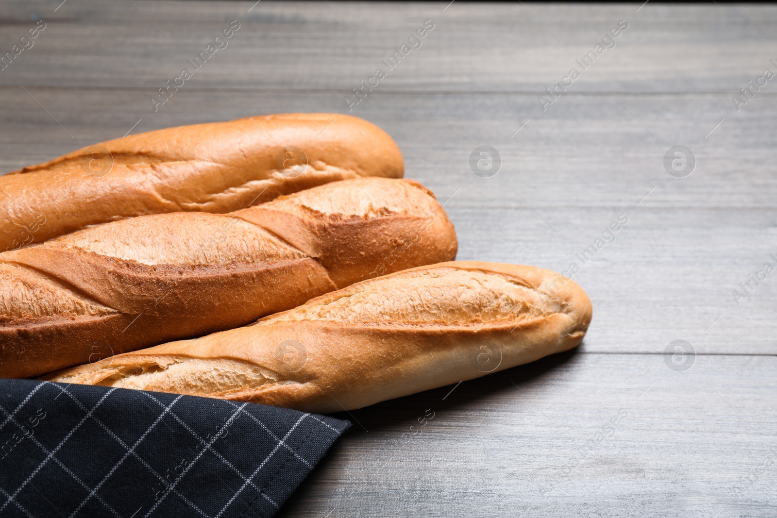 Photo of Tasty baguettes on wooden table, closeup. Space for text