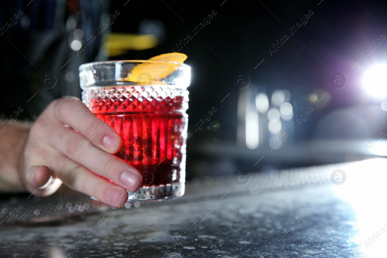 Photo of Barman holding fresh alcoholic Red Russian cocktail on bar counter, closeup. Space for text