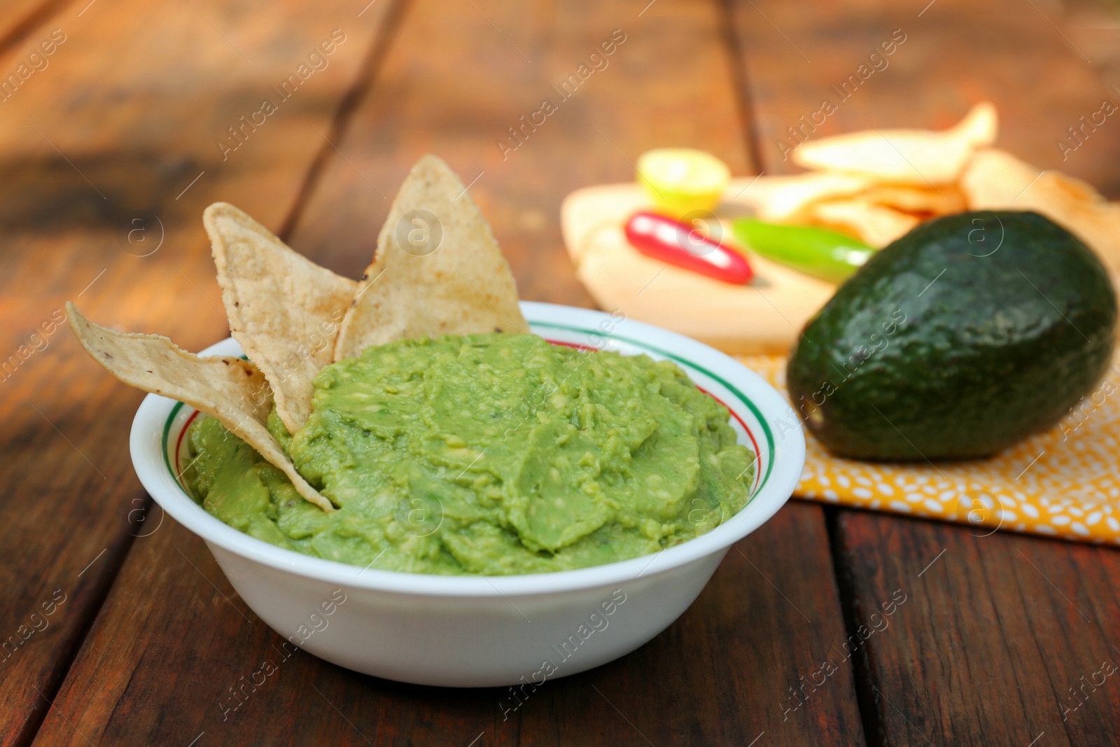 Photo of Delicious guacamole made of avocados with nachos on wooden table