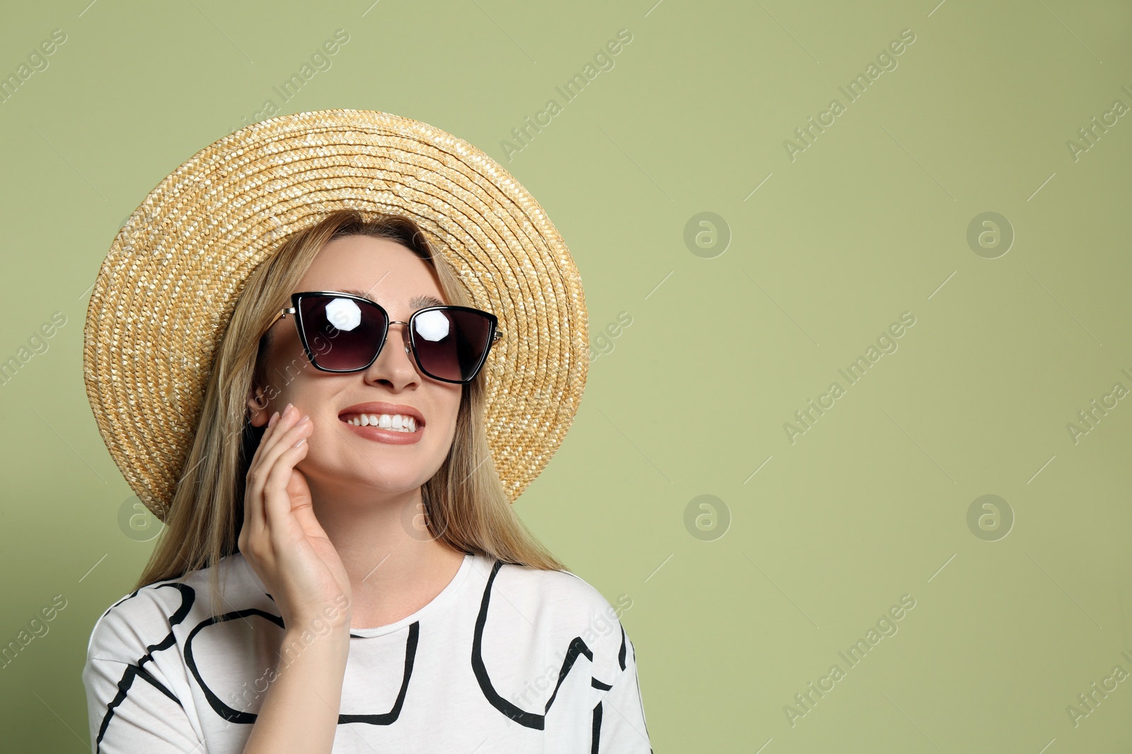 Photo of Beautiful young woman wearing straw hat and sunglasses on light green background, space for text. Stylish headdress